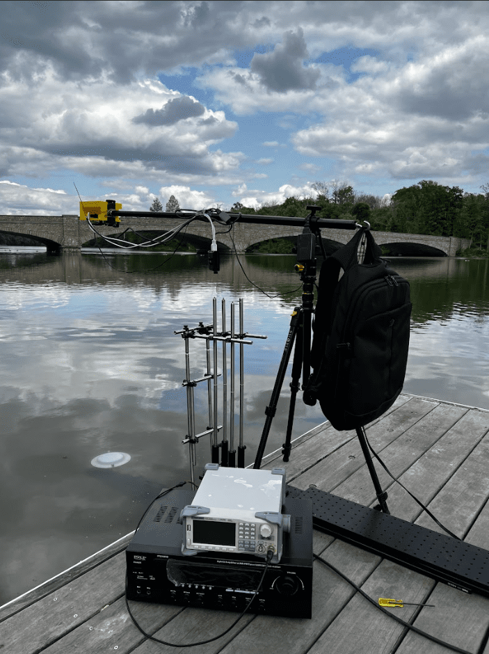 Equipment on a wooden platform on a lake with a stone bridge in the background